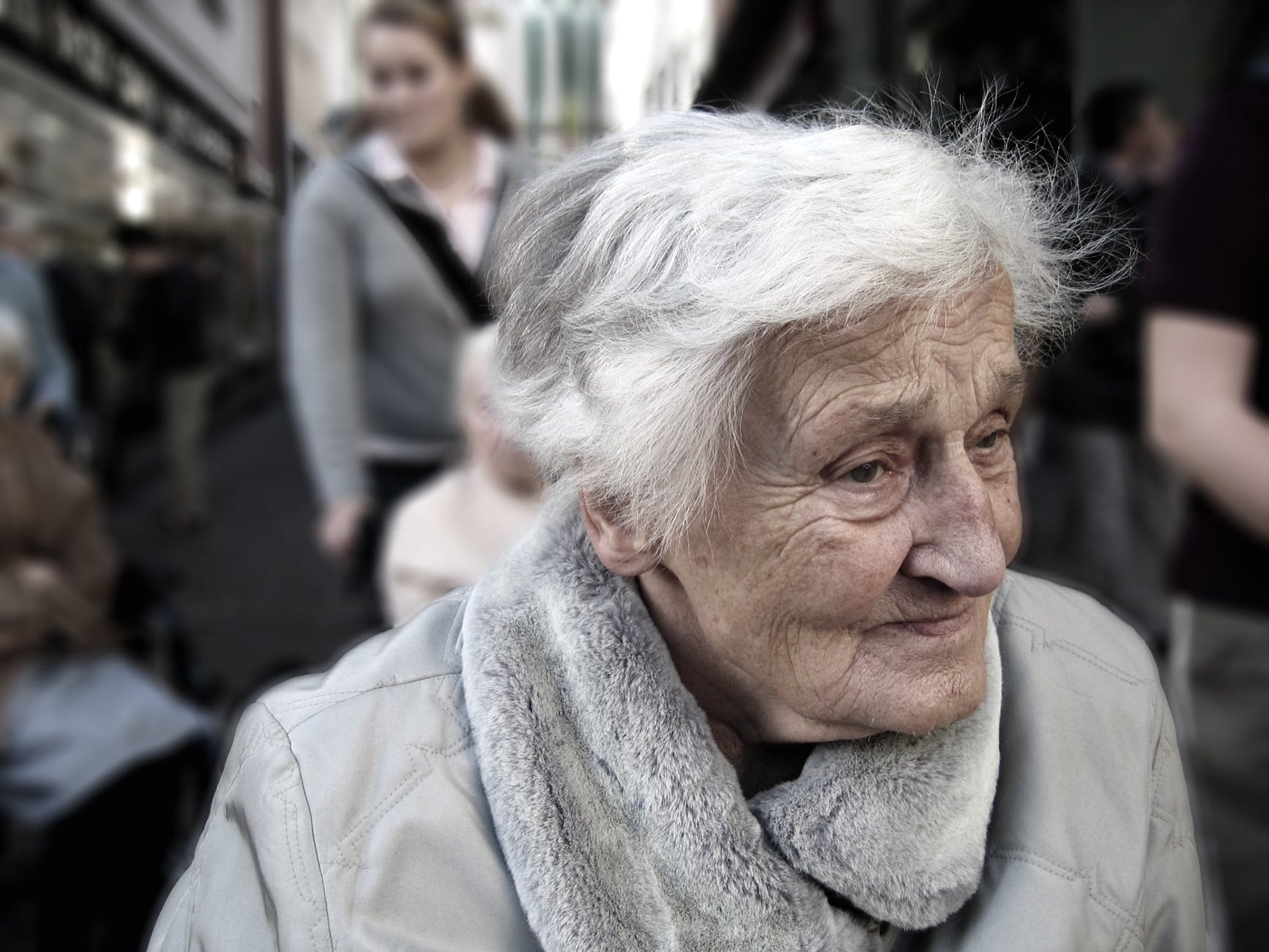 woman wearing gray scarf and gray coat near group of people